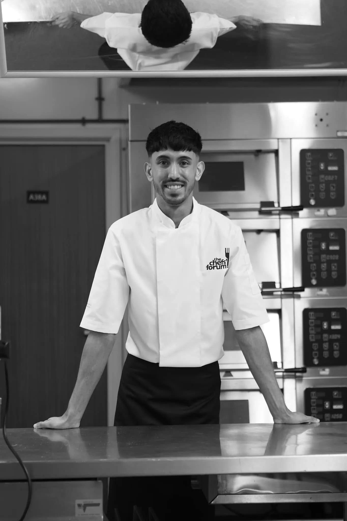 Chef Jubz in a commercial kitchen, monochrome portrait.